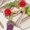 Lacets brodés rayés crème et gris tourterelle « Peaux » avec trois breloques en perles en forme de fruits