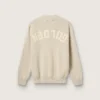Pull unisexe à col rond en coton beige, avec un patch sur le devant et un logo dans le dos